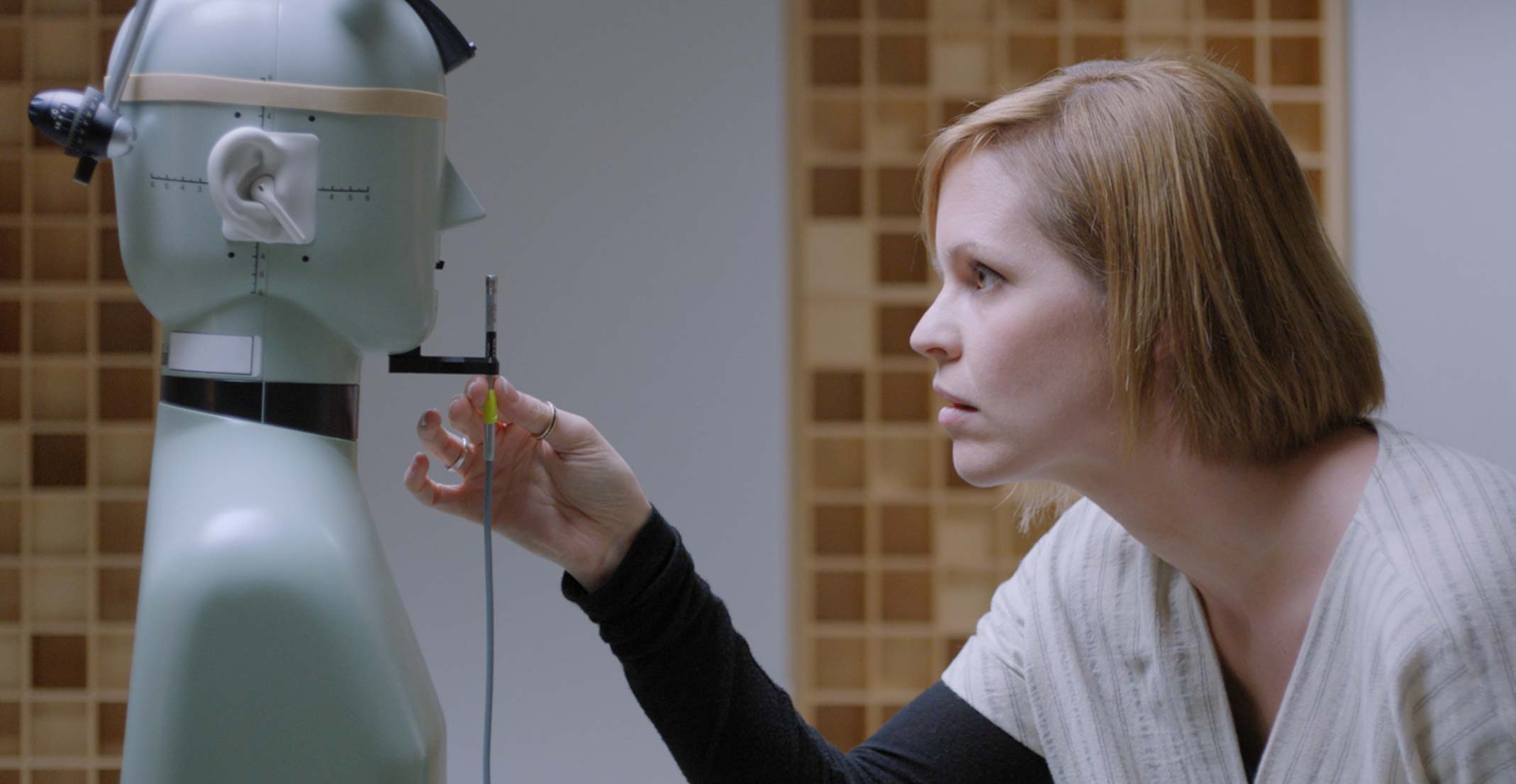 A Suzie, gerente de um grupo de protótipos acústicos, ajusta um microfone na frente de um manequim em um laboratório de engenharia em Cupertino.