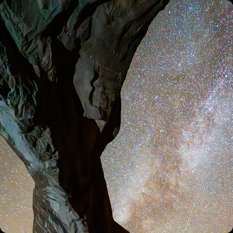 満天の星空を背景に、柱のような岩が写っている写真