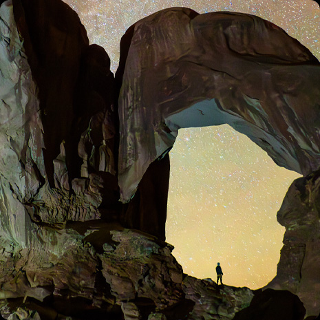 満天の星空のもとで峡谷に立つ1人の人物の写真